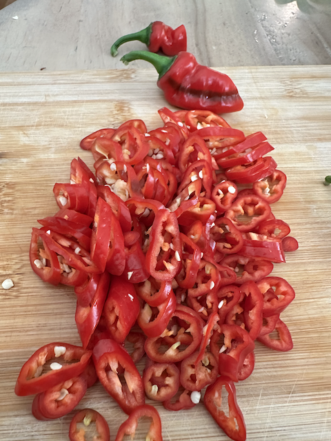 Jimmy Nardello peppers whole and sliced on cutting board