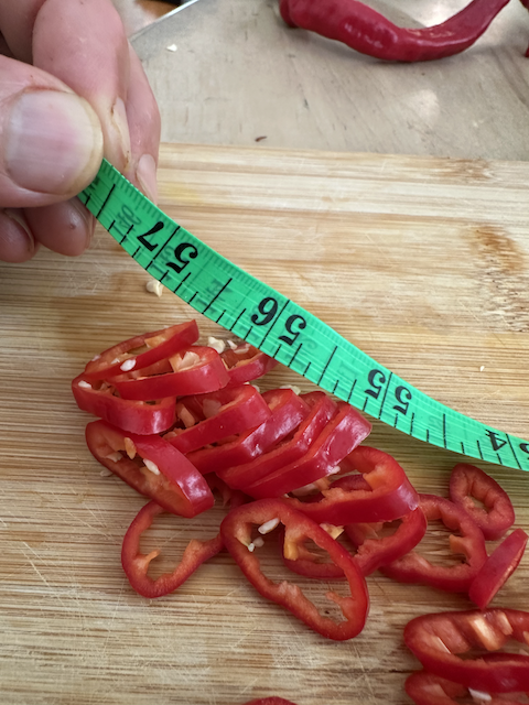 Thinly sliced Jimmy Nardello peppers with tape measure