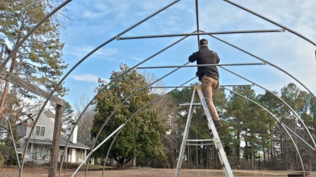 Installing the center purlin on the high tunnel